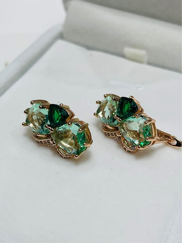Close-up of 14k rolled gold butterfly earrings, showcasing the intricate setting of green gemstones.