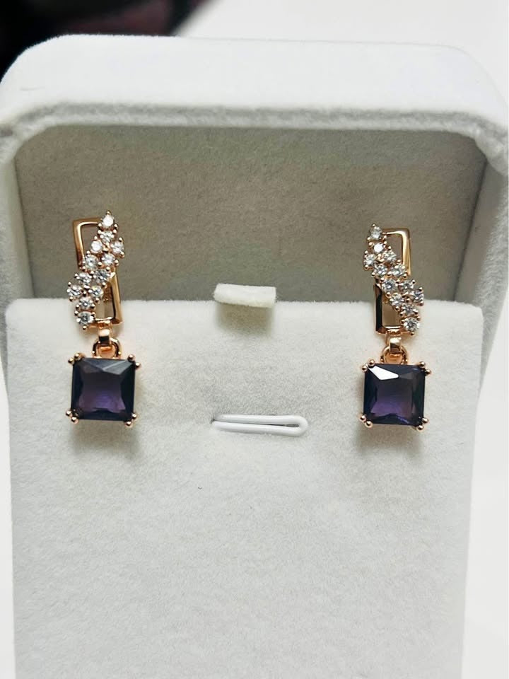 Fancy 14k rolled rose gold earrings featuring a deep purple amethyst and a wavy crystal design.