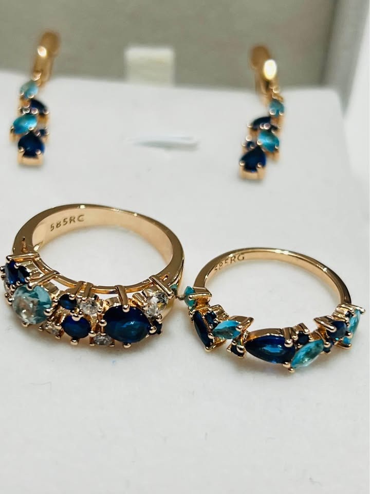 A matching set of 14k rolled gold earrings and rings with blue and light blue gemstones.