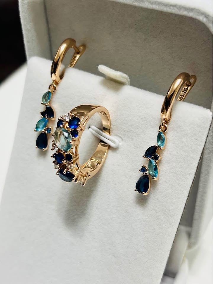 A jewelry set of 14k rolled gold earrings and a ring, adorned with various shades of blue gemstones.