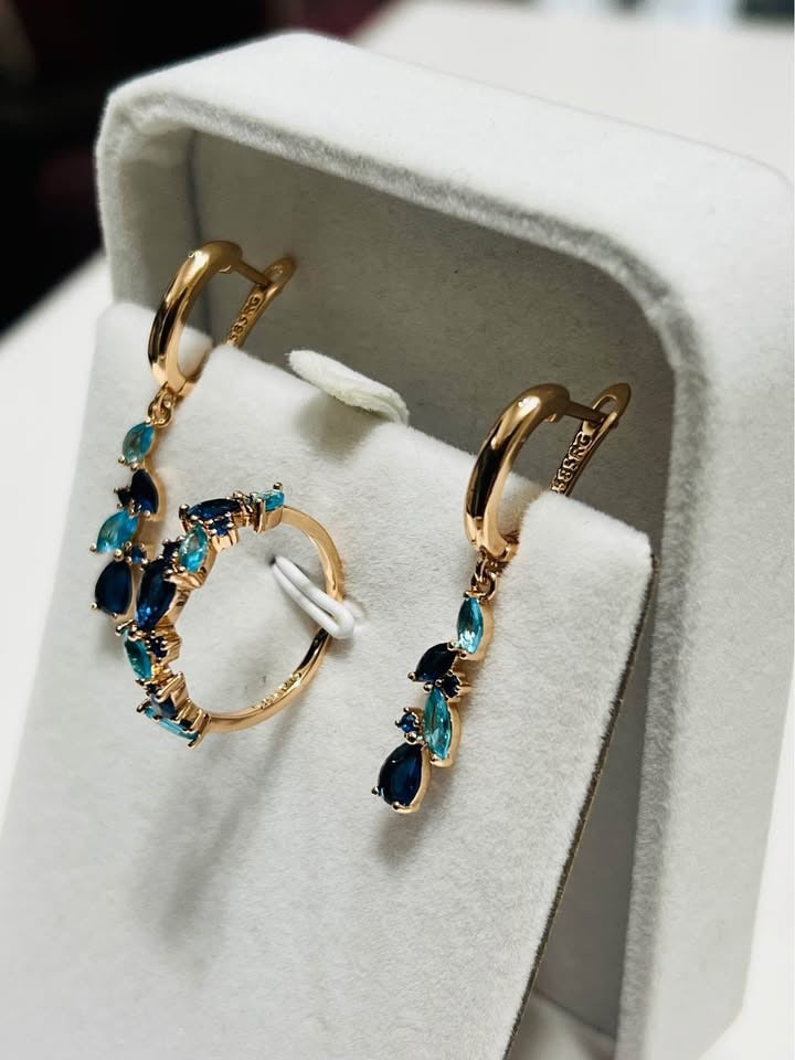 A 14k rolled gold earring and ring set featuring a cascading design of blue topaz and sapphire gemstones.