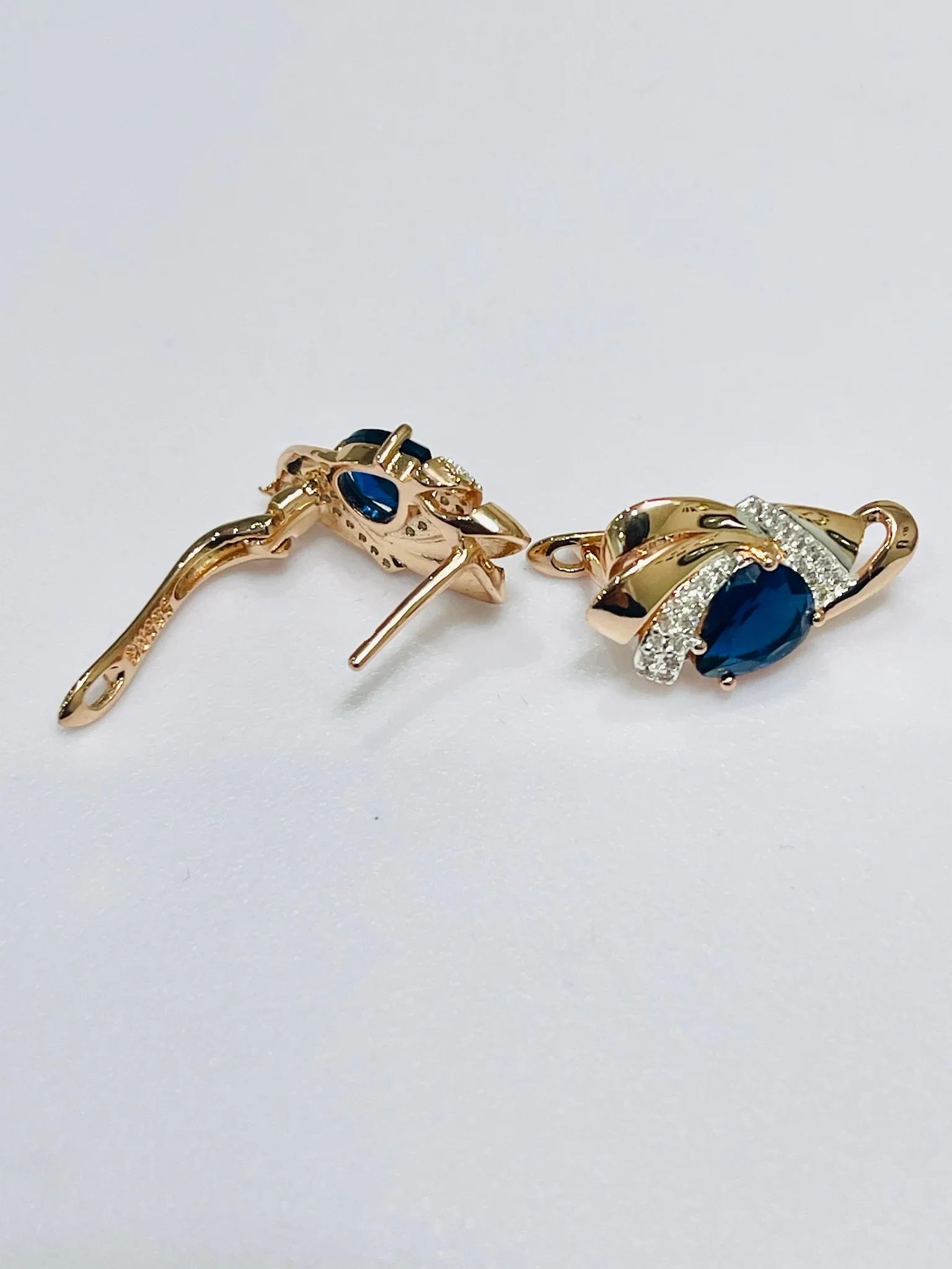 Gold earrings with blue gemstones on a light gray background