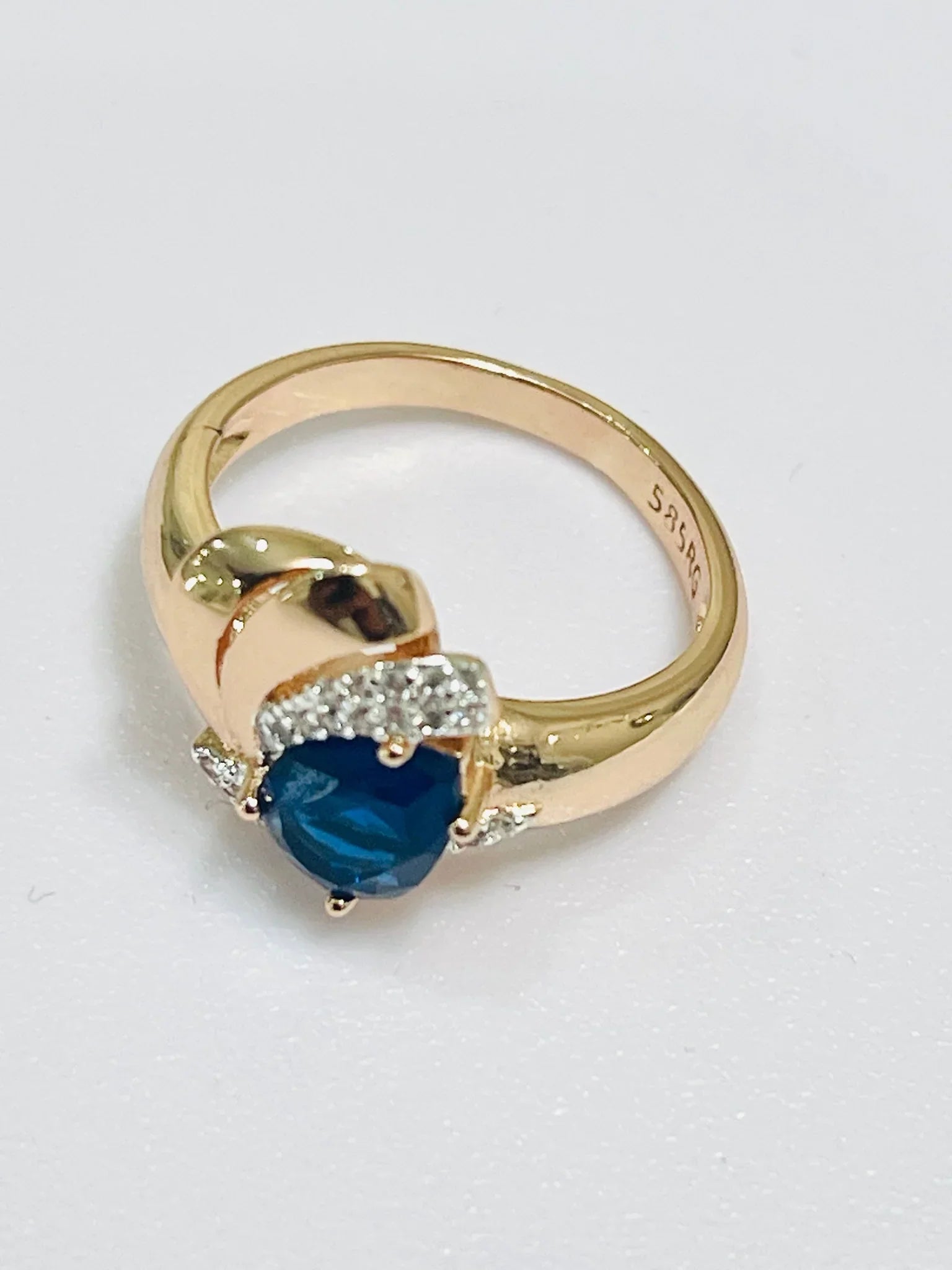 Gold ring with a blue gemstone and diamonds on a white background