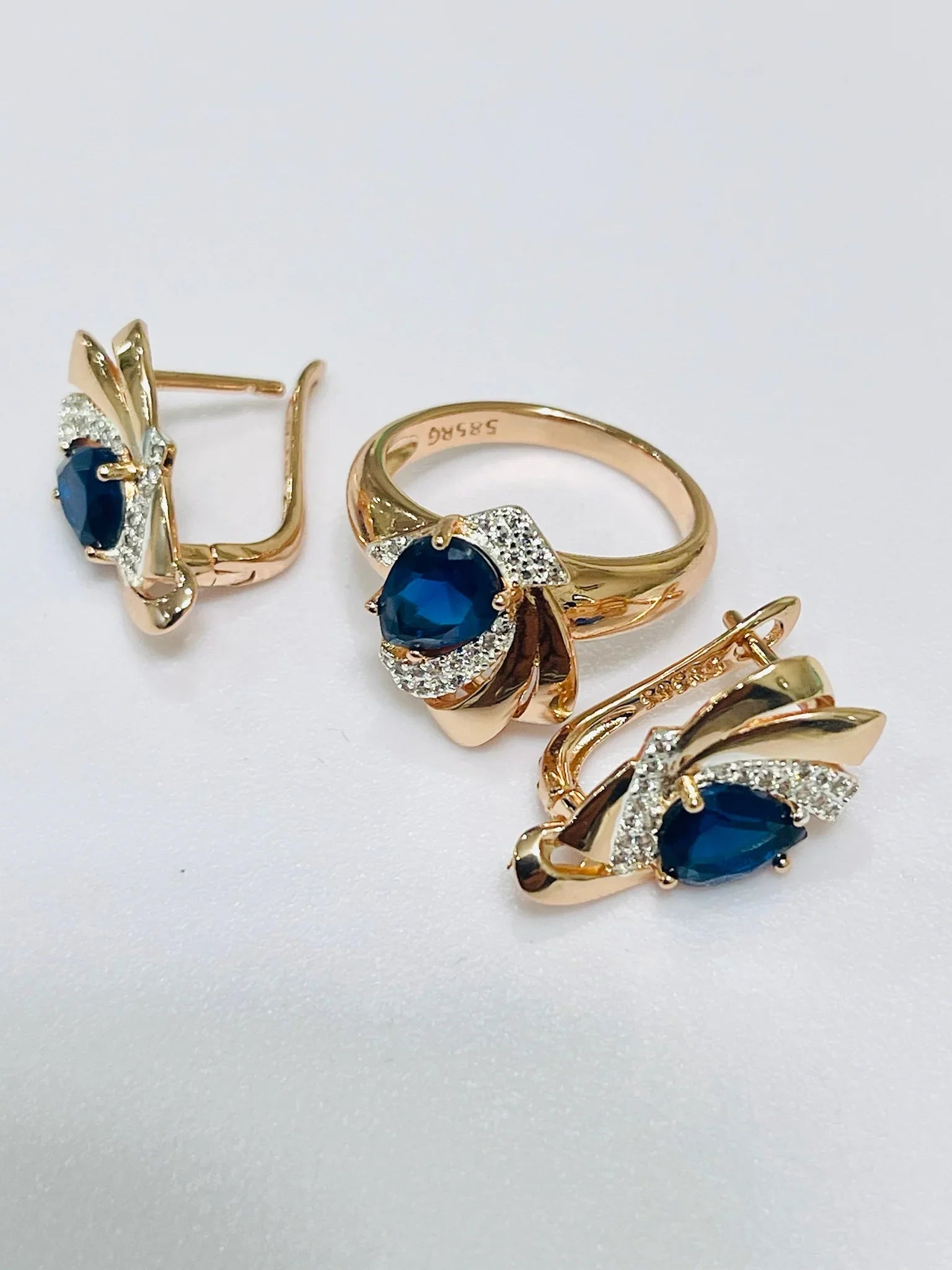 Gold jewelry set with blue gemstones on a white background