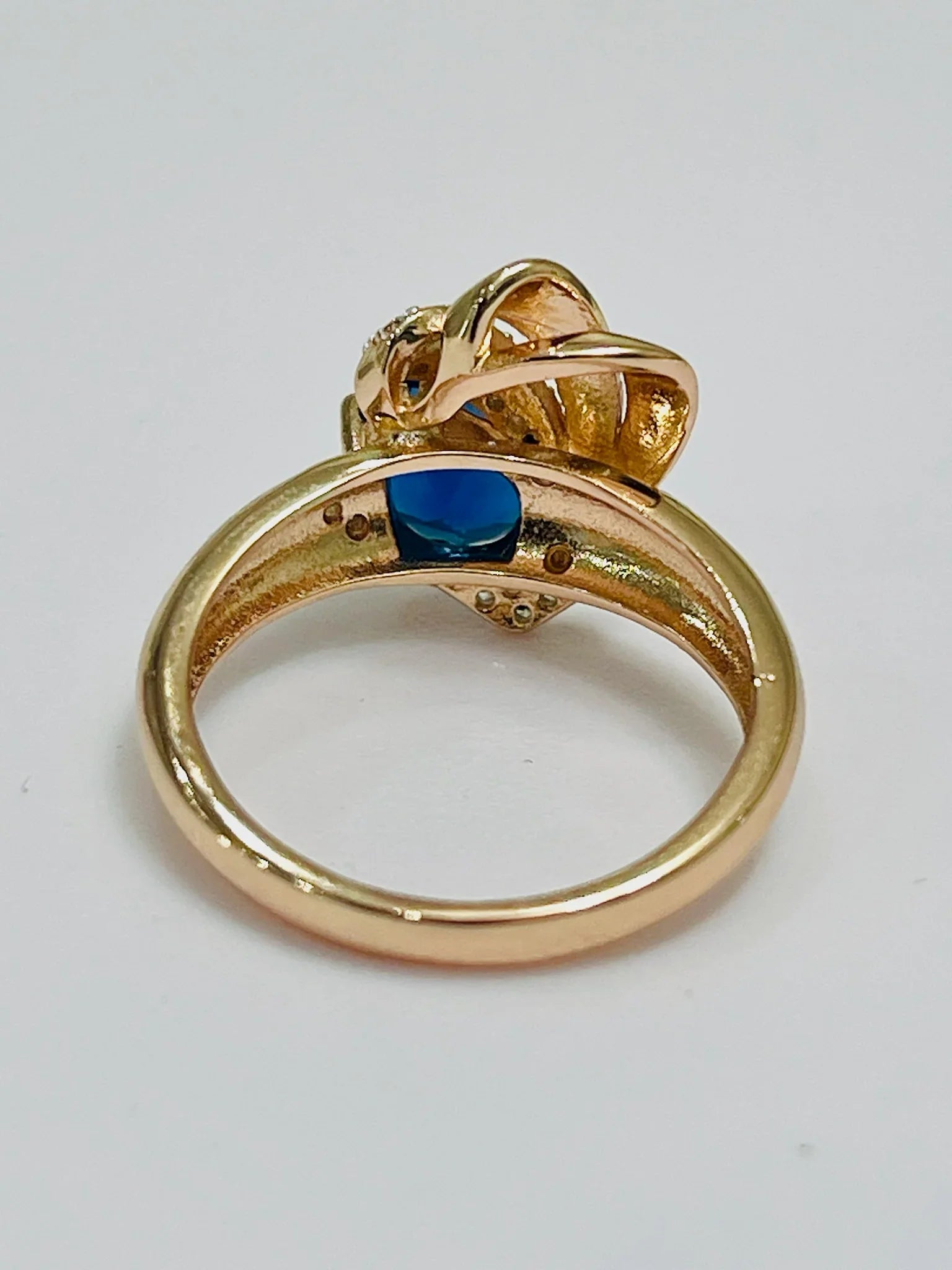 Gold ring with a blue gemstone on a light gray background