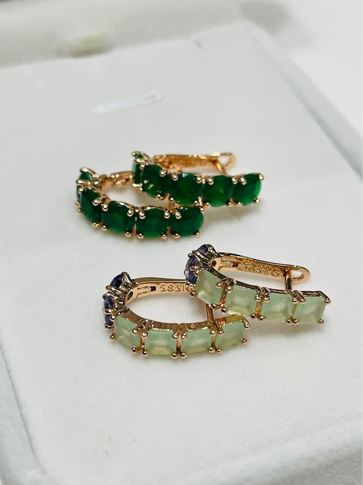 Two pairs of elegant 14k rolled gold huggie hoops, one with solid green stones, the other with varied colors.