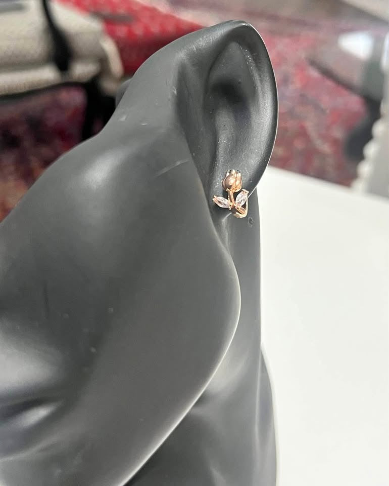 Small rose gold tulip huggie hoop earrings, shown on a display mannequin.