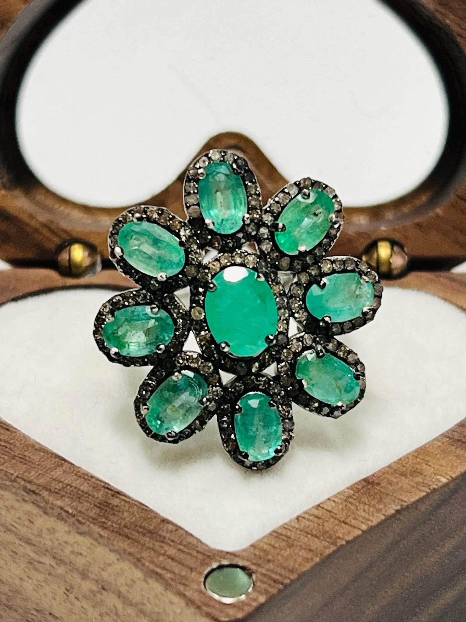 Exquisite sterling silver floral ring with a central emerald and sparkling diamond accents, on display.