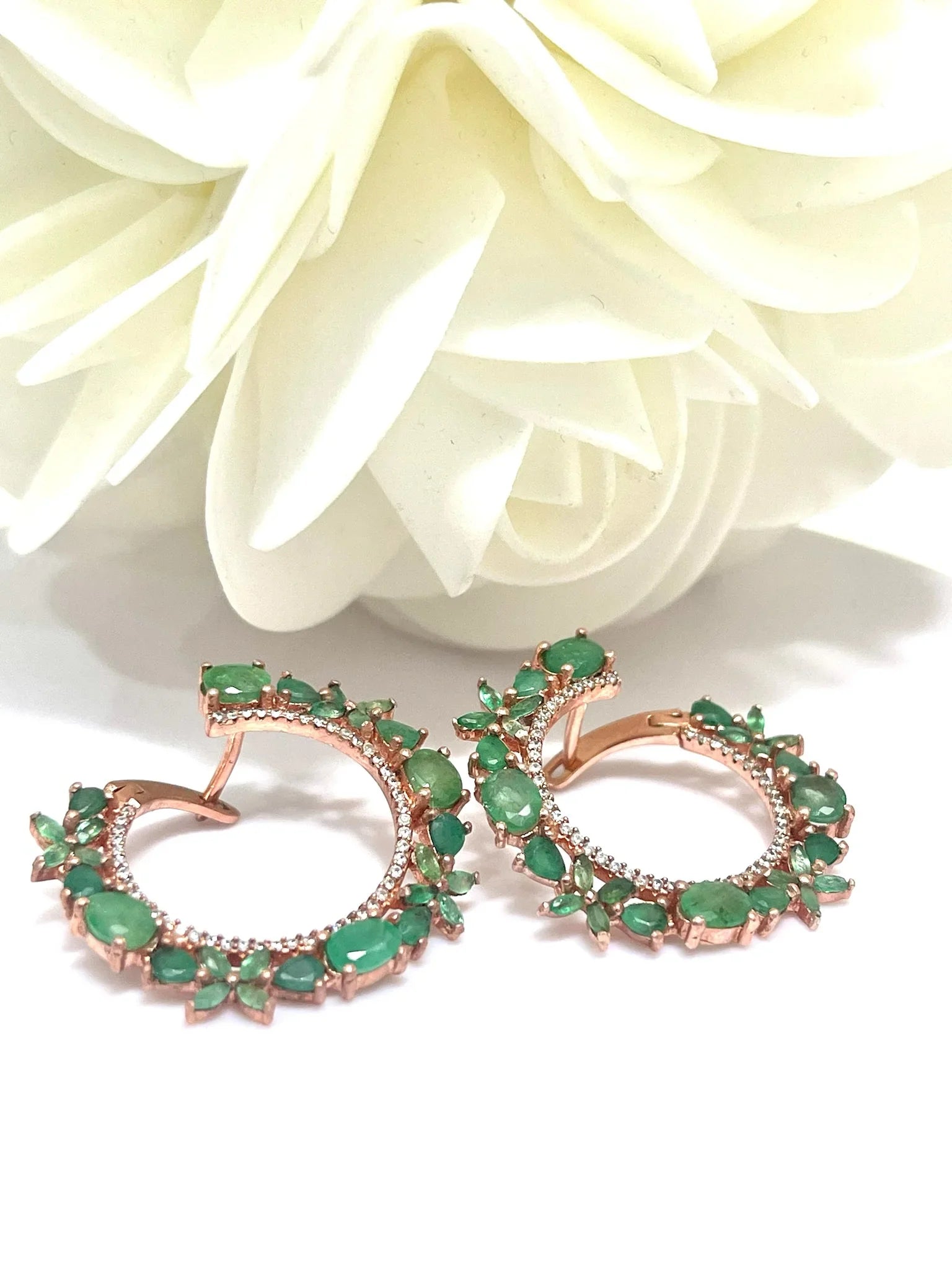 Pair of handmade emerald and rose gold plated hoop earrings on a white surface, angled to show the floral design