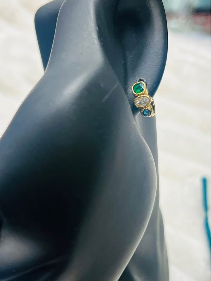 Close-up of a tri-gemstone 18k gold vermeil huggie earring worn on a mannequin ear.