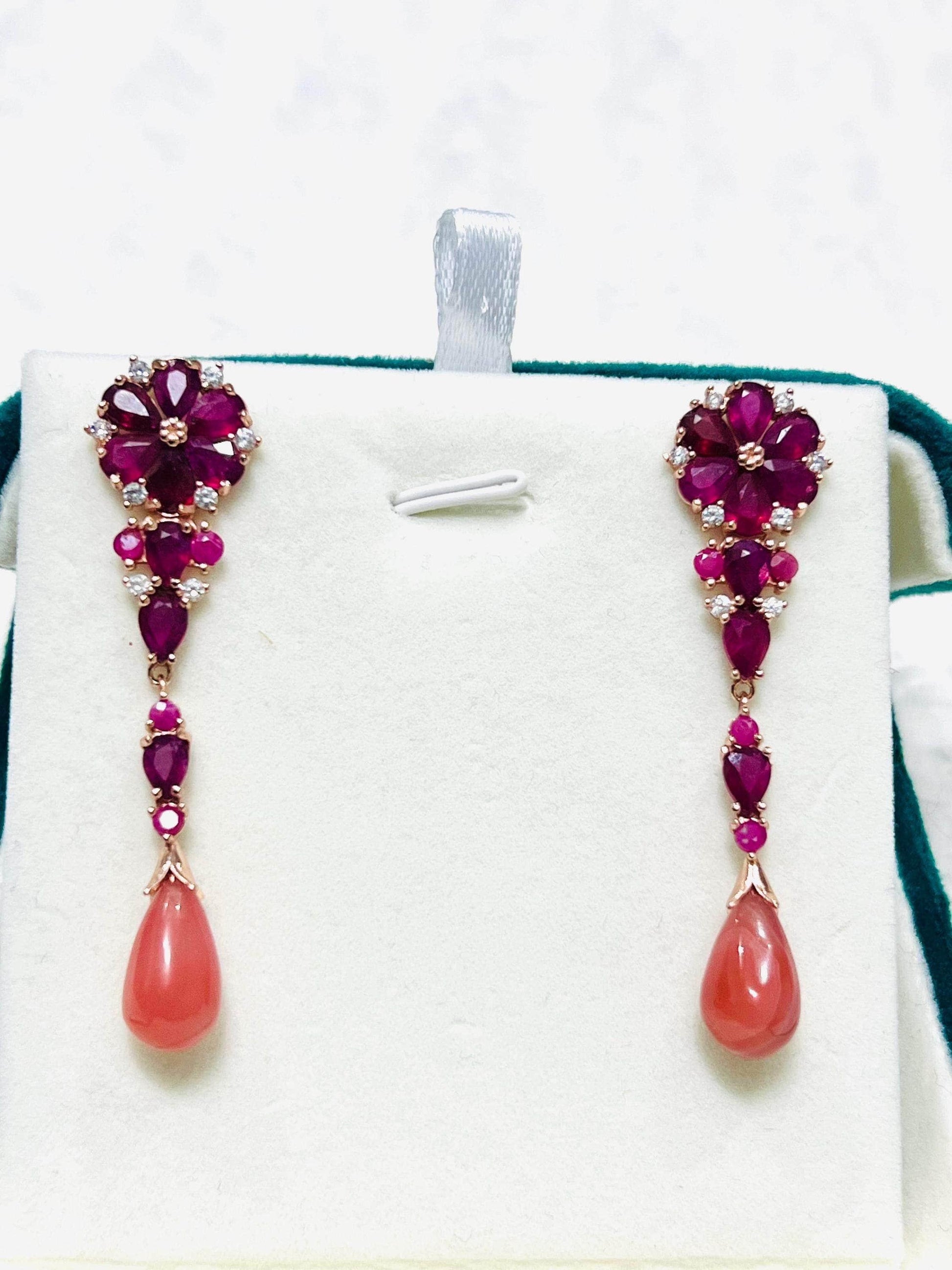 Pair of elegant dangle earrings with red rubies, sparkling accents, and teardrop prehnite, displayed straight.