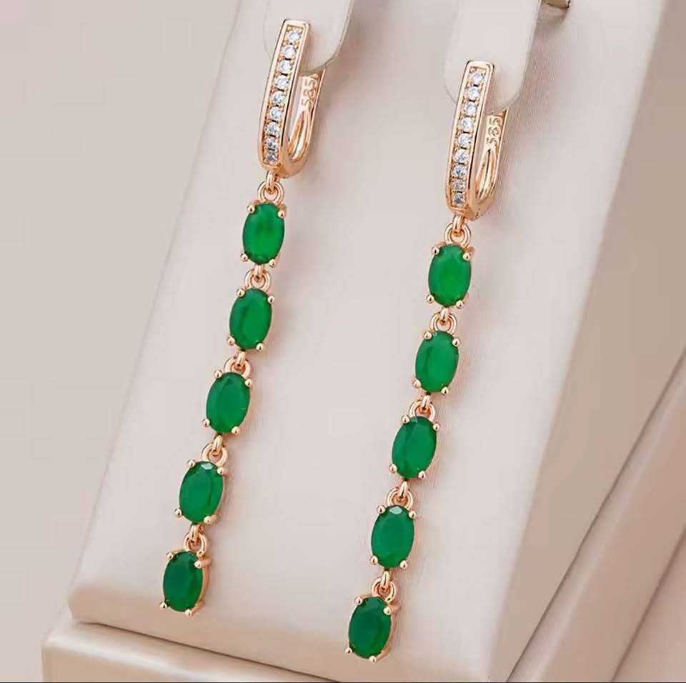  Frontal view of 14K 585RG stamped long fancy earrings with oval emeralds and brilliant diamonds, on a display stand.