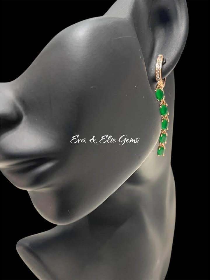 Close-up of 14K 585RG stamped emerald long fancy earrings on a jewelry display head, highlighting the gems.