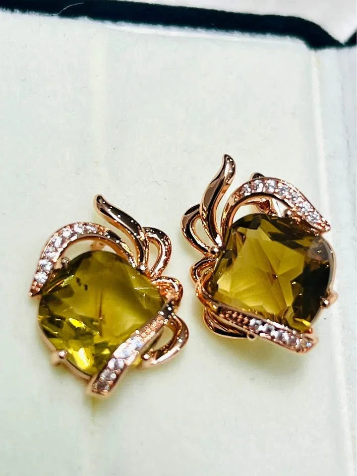 A pair of 14k gold-filled earrings with a leaf-like design surrounding a large, natural citrine stone.