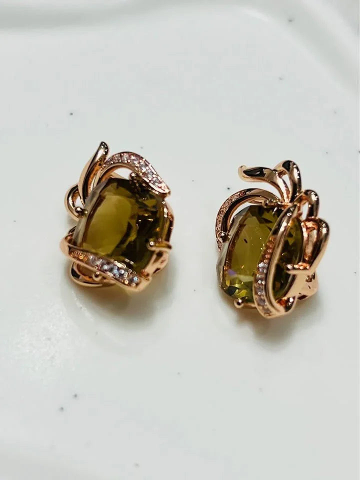 A close-up of a pair of 14k gold-filled earrings featuring large, amber-colored citrine stones in a detailed setting.