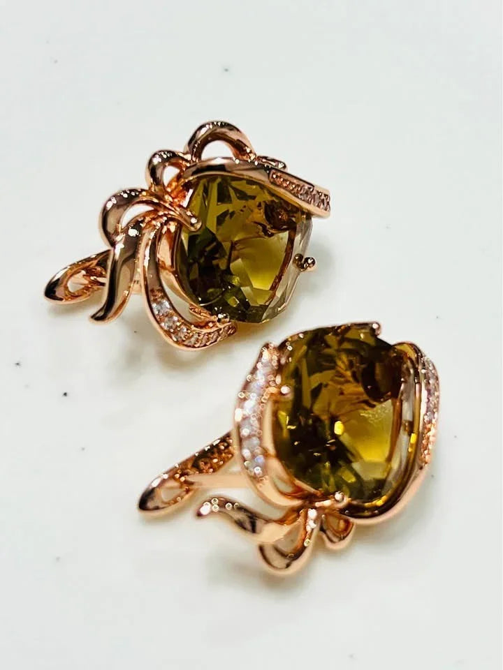  A pair of stunning 14k gold-filled stud earrings with large citrine gems and a delicate, swirled metal design.