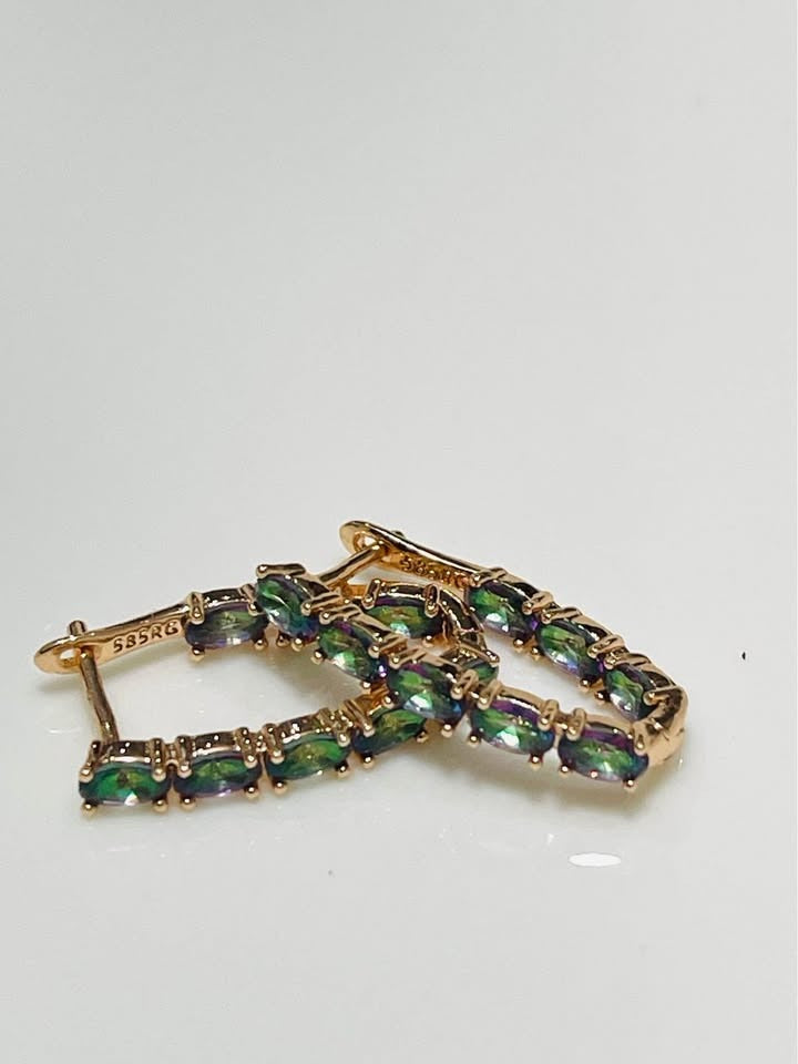 A pair of 14k rose gold-filled V-shaped hoop earrings featuring a full row of striking green tourmaline gemstones.