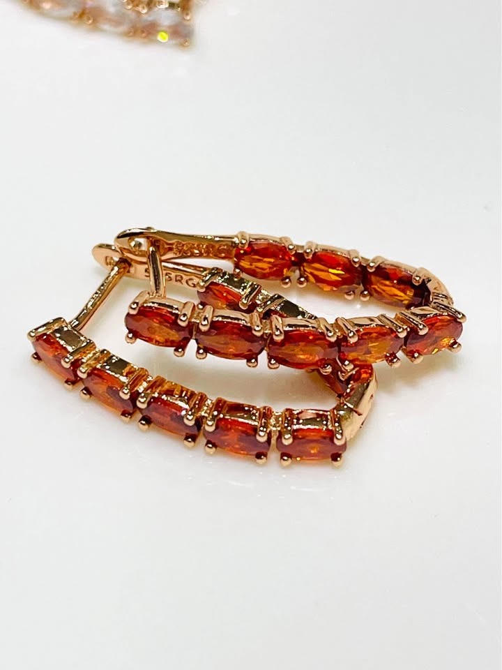 A pair of 14k rose gold-filled V-shaped hoop earrings adorned with bright orange tourmaline stones.