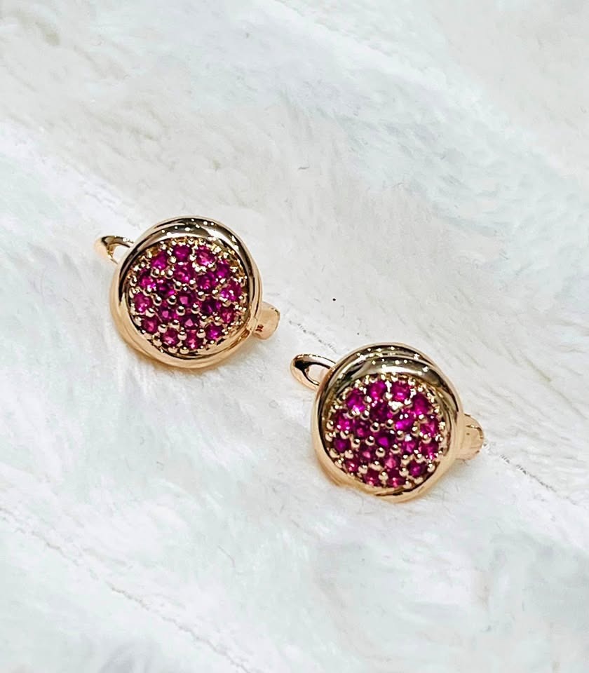 Close-up of 14k rose gold dainty pink zircon earrings resting on a white furry surface.