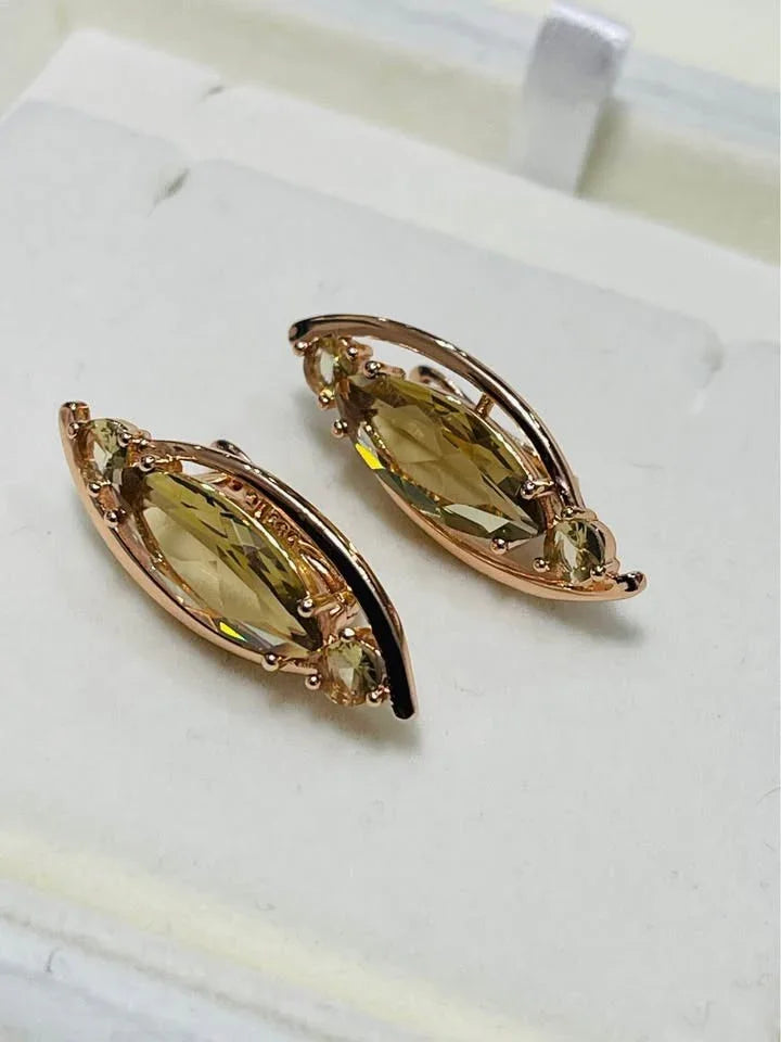 Angled view of elegant 14k rolled gold earrings, each with a central marquise citrine gemstone.