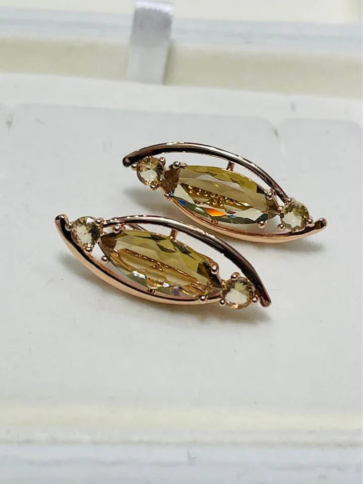 A pair of 14k rolled gold earrings featuring a large marquise-cut citrine stone and smaller accent gems.