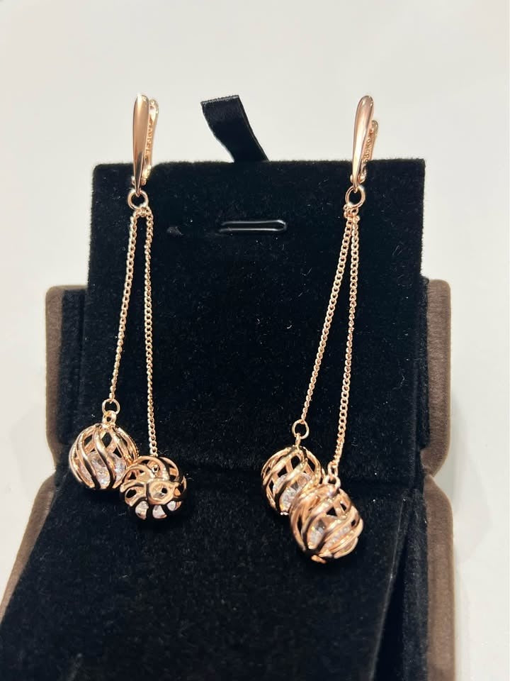 A pair of 14k rolled gold 585RG stamped natural zircon dangle earrings neatly displayed in a velvet box.