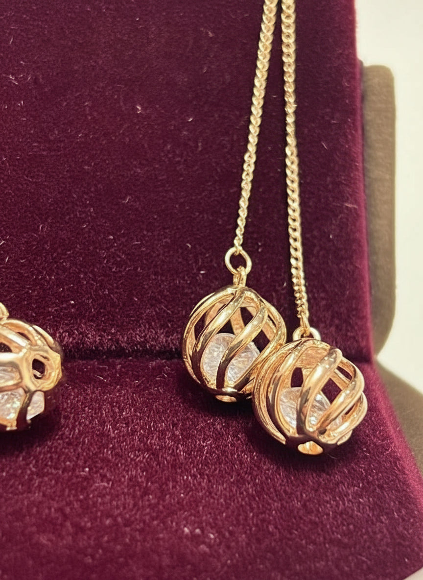 Close-up of 14k rolled gold 585RG stamped dangle earrings, highlighting the caged natural zircon design.