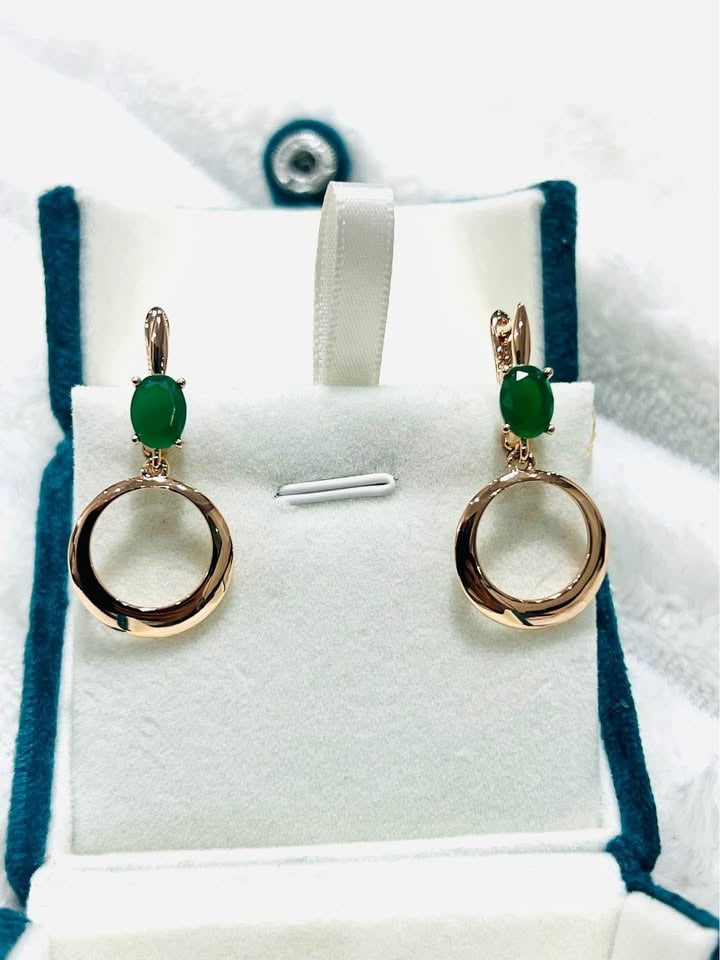 14k rose gold dangle earrings with oval-cut emeralds and a suspended open circle design.