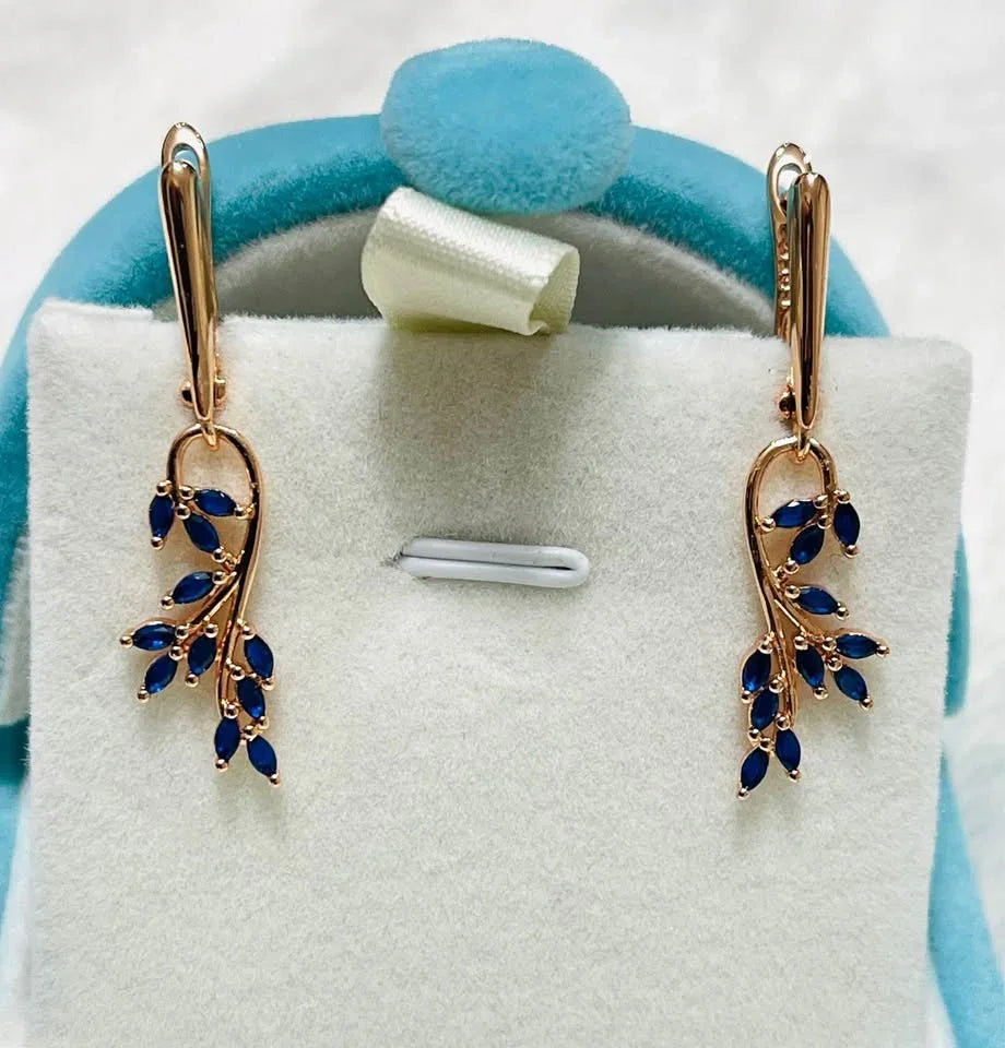 Pair of 14K rose gold stamped earrings with a delicate leaf design and natural blue sapphire gemstones.