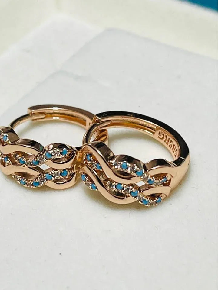 A pair of 14k 585 rose gold huggie hoop earrings with a beautiful turquoise and wave design.