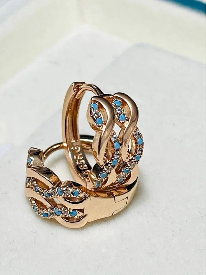 A pair of 14k 585RG rose gold turquoise huggie hoops with a unique wave design, shown stacked.