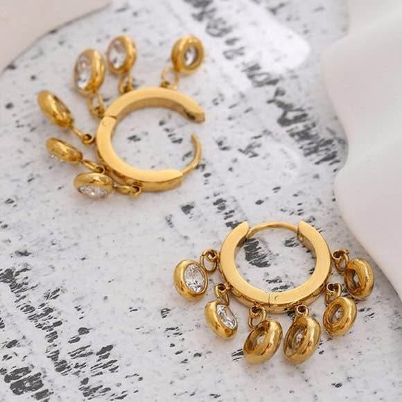 Overhead view of 18k gold vermeil fan hippie dangle earrings with charming charms on a textured surface