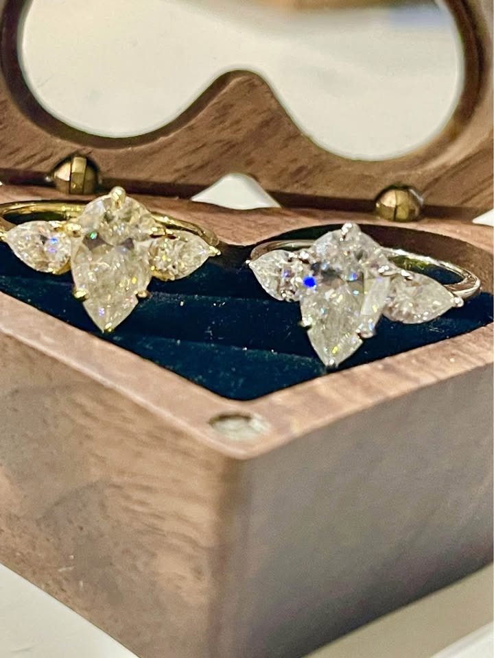 Side view of 18k gold and sterling silver moissanite rings, each 4 carats, with pear-shaped center stones.