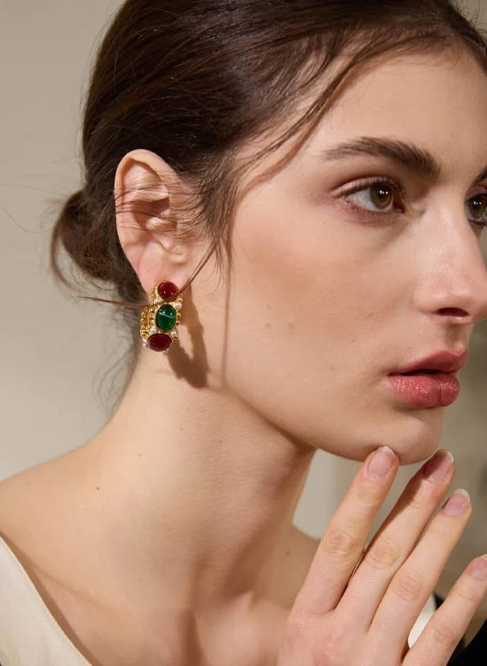 Model wearing luxurious 18k gold vermeil East West earrings with vibrant green and red gemstones and pearls.