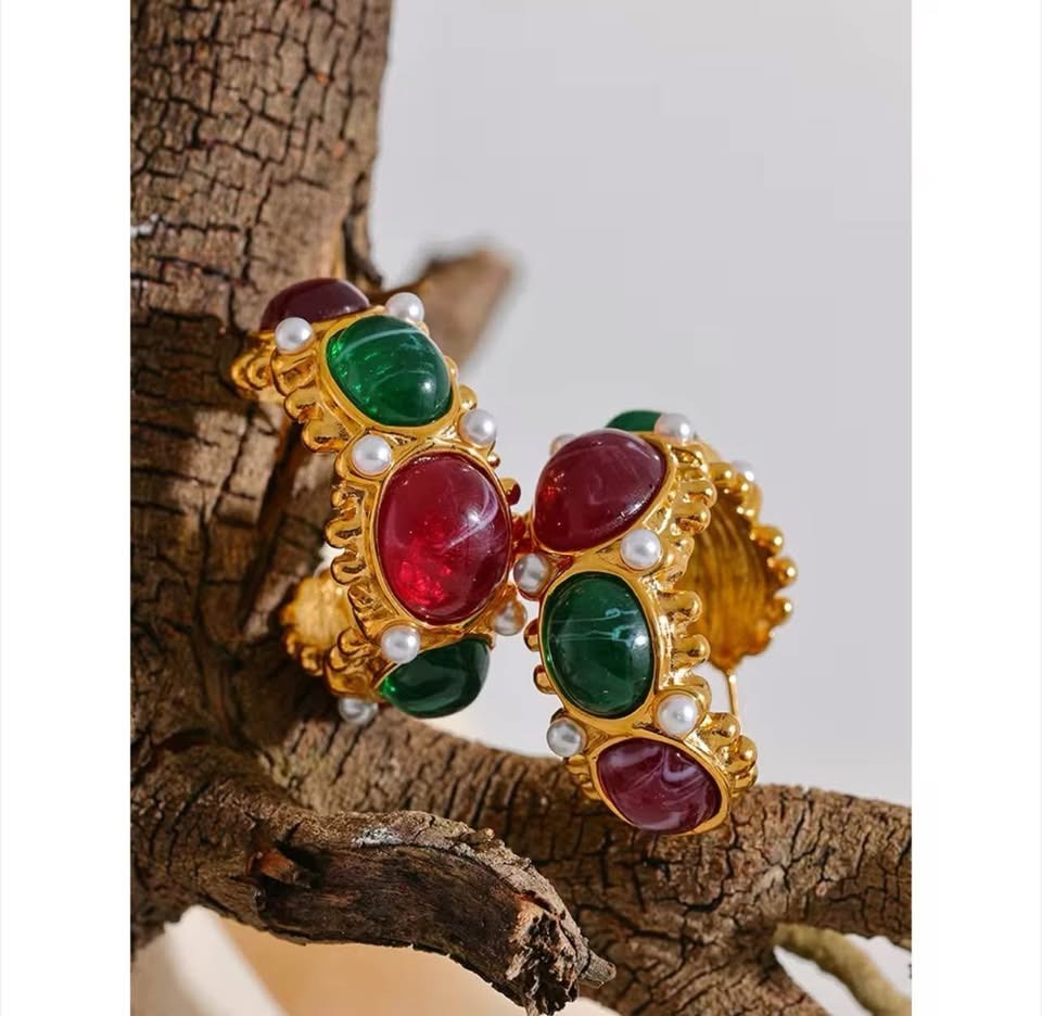 Pair of 18k gold vermeil East West earrings with rich green and red cabochon gemstones, displayed on a branch.