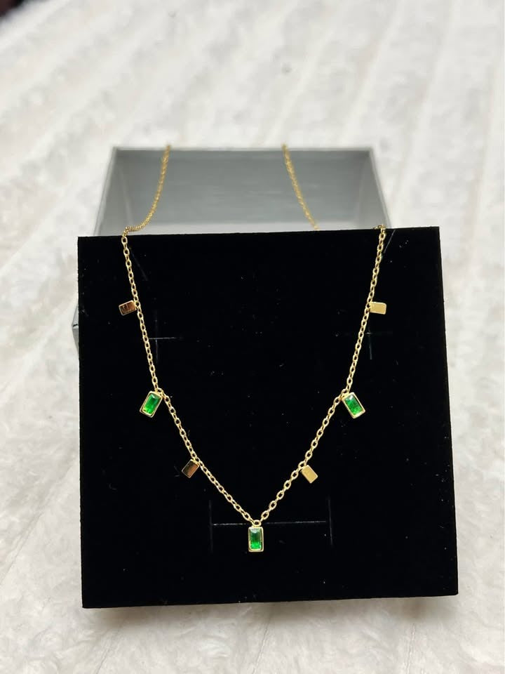 Angled shot of a stunning 18K gold vermeil emerald necklace, with green stones displayed in a black jewelry box.