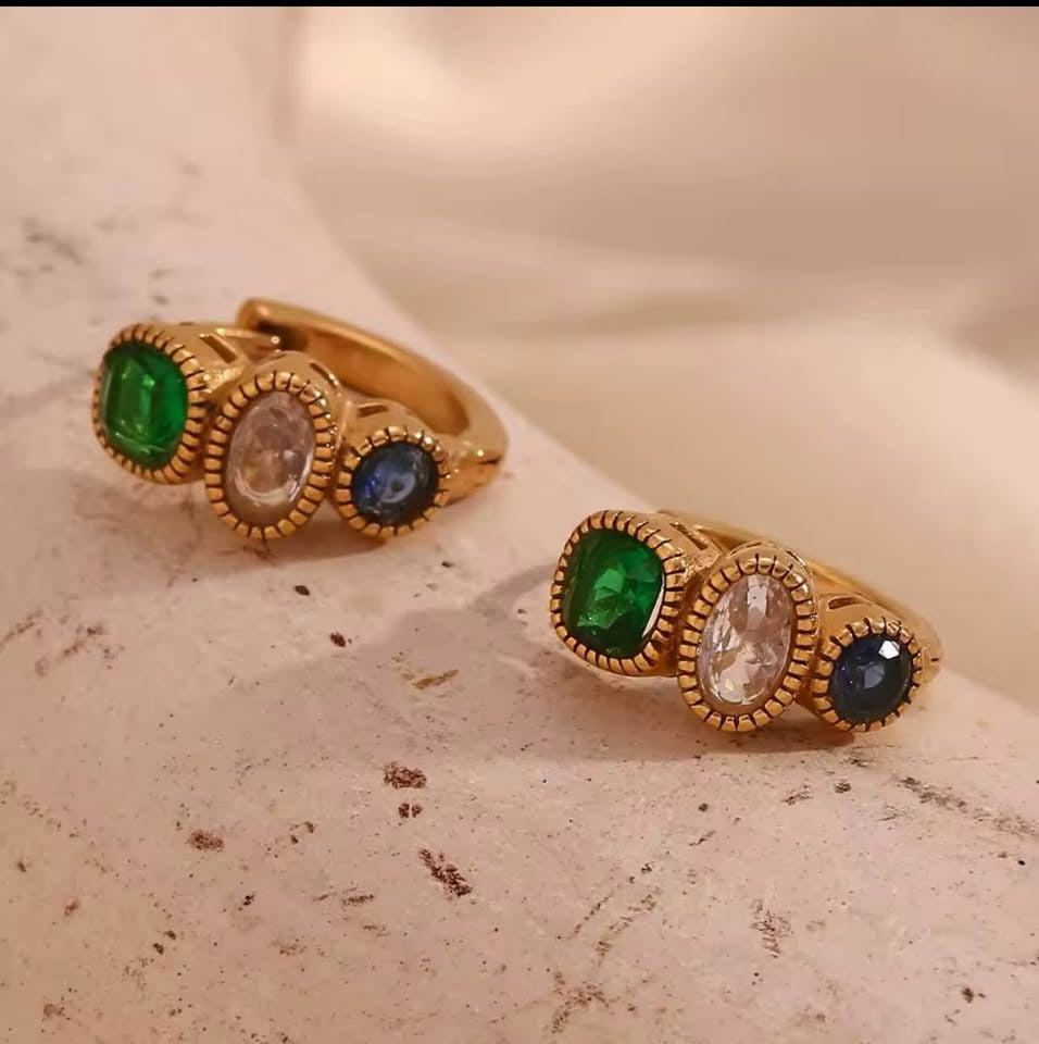 18k gold vermeil huggie earrings featuring three oval-cut gemstones: green emerald, clear quartz, and blue sapphire.