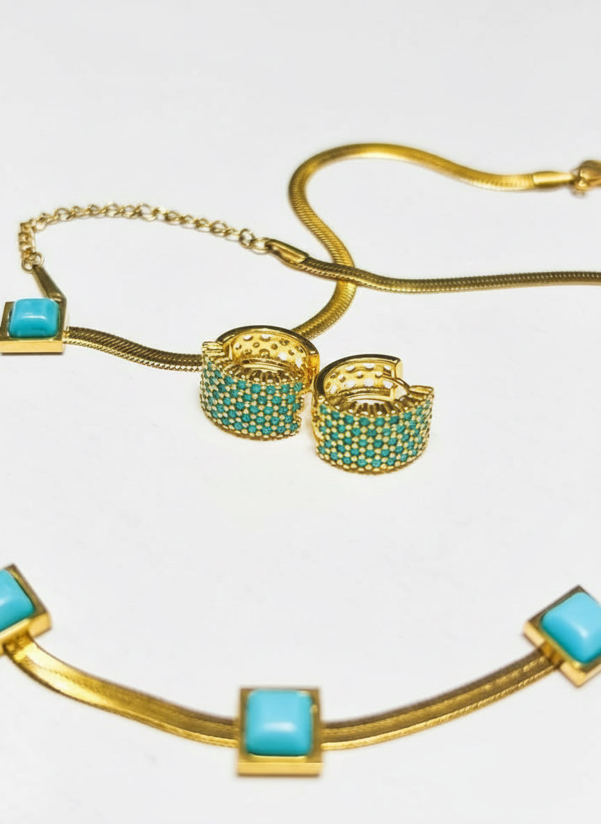 Close-up of 18k gold vermeil waterproof huggie hoop earrings with turquoise stones.