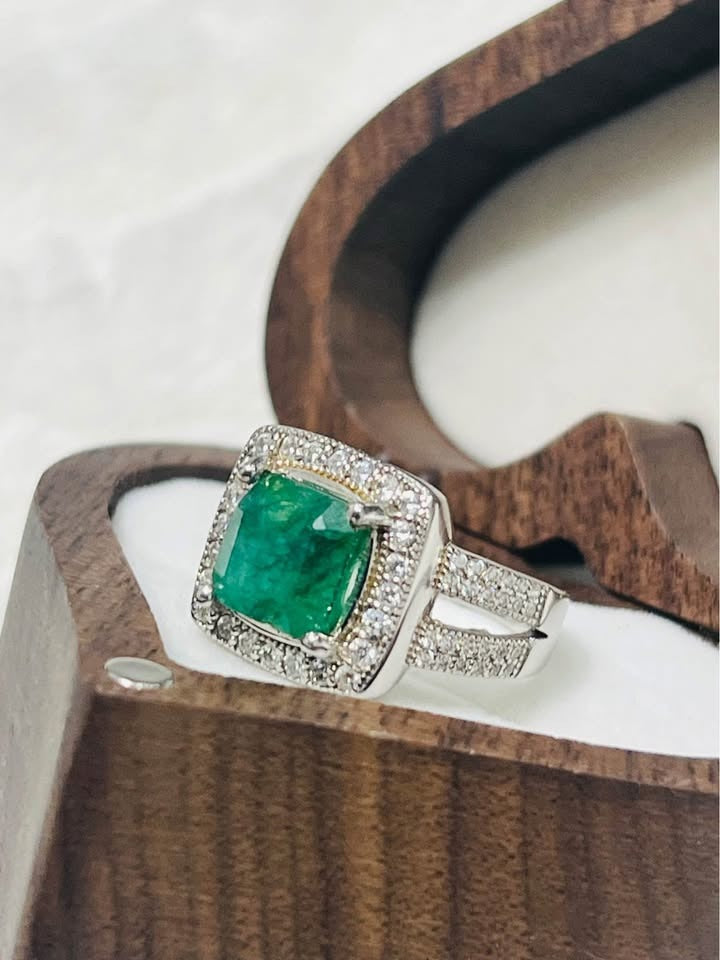 Close-up side view of a 2 carat natural emerald ring featuring a diamond halo and sparkling split shank.