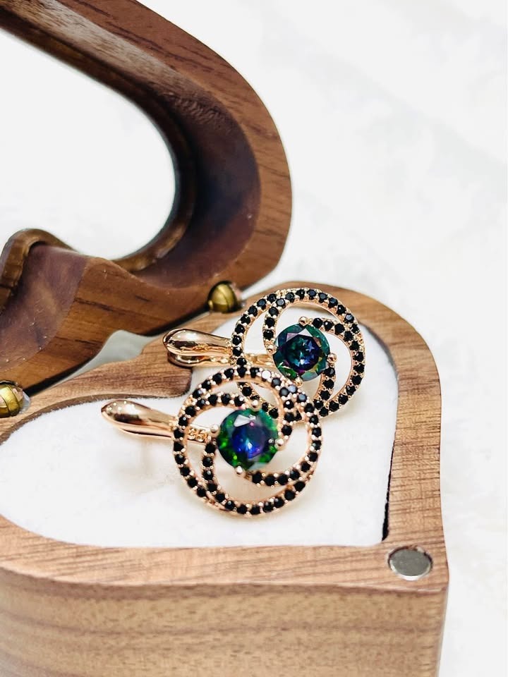 Top-down shot of 585RG rose gold earrings with colorful mystic topaz and dark accents, resting in a gift box.