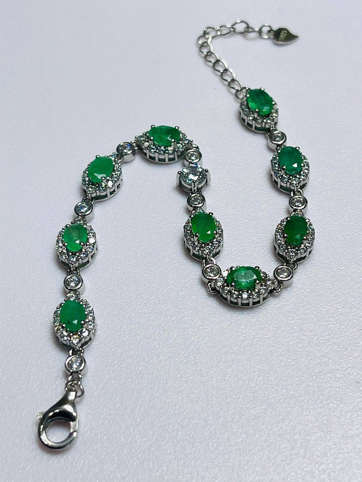 Elegant sterling silver bracelet with oval Colombian emeralds, featuring a secure lobster clasp and adjustable chain for fit.