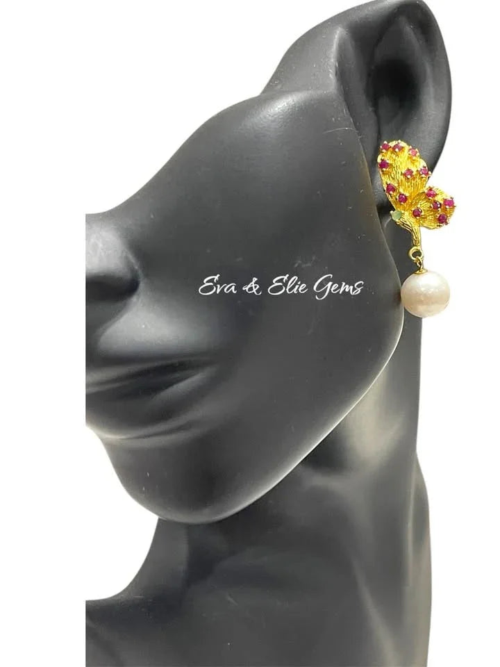 Handmade sterling silver butterfly earrings with rubies, emeralds, and pearls, worn on a mannequin ear.