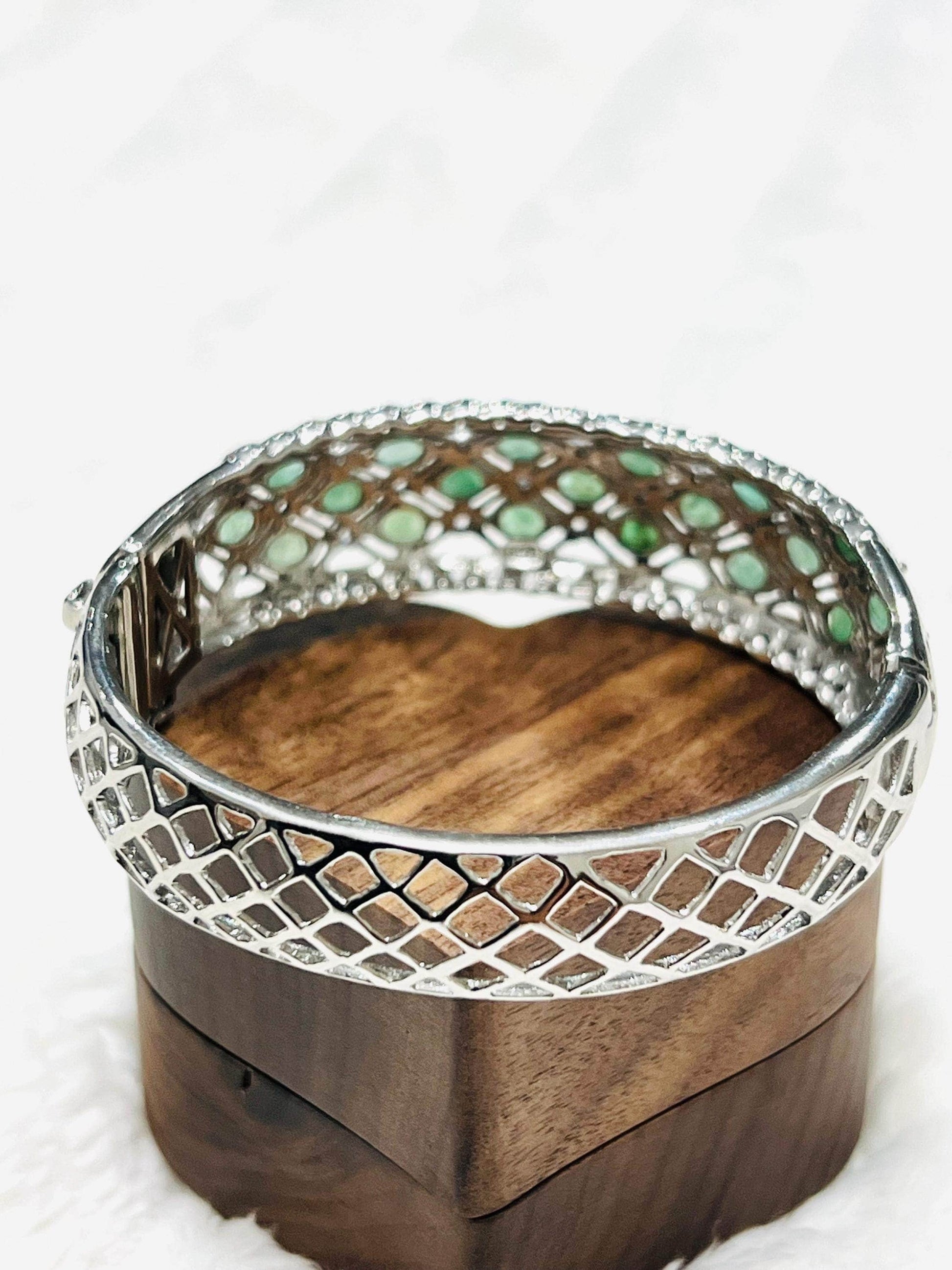 Aztec sterling silver bangle with emeralds and tanzanites, showing its open clasp and lattice design.