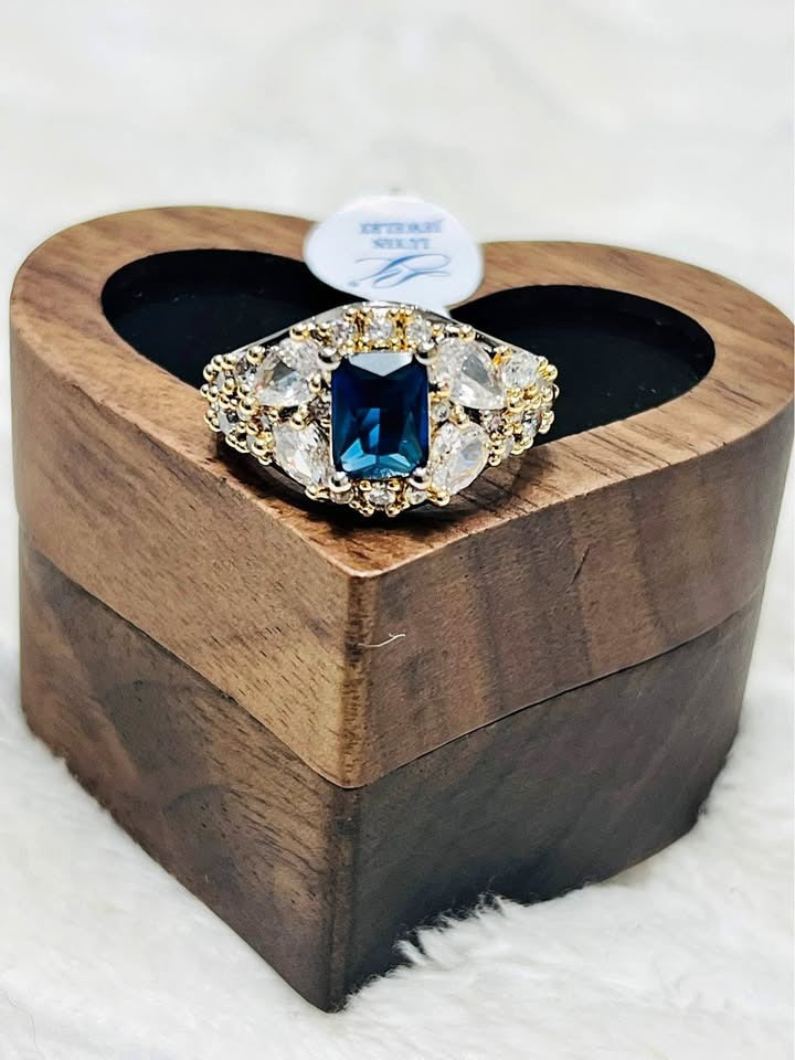 Close-up of a beautiful shining sapphire and diamond ring in a heart-shaped wooden box, front view.