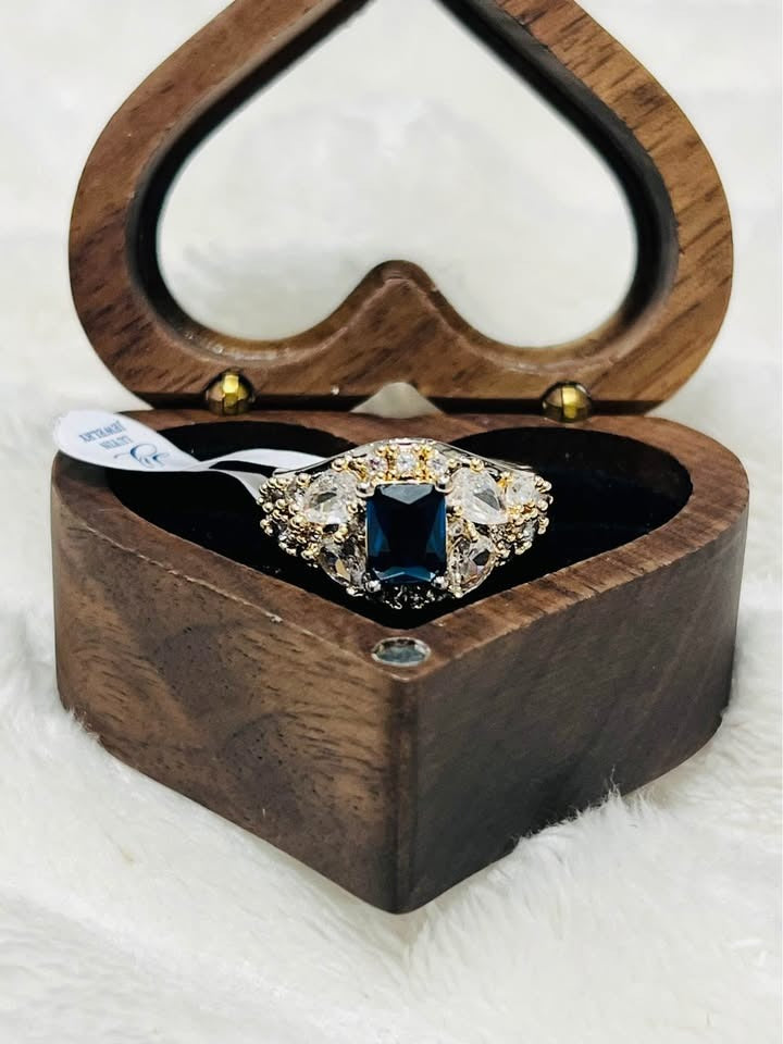 Beautiful shining sapphire and diamond ring with tag, showcased in an open heart-shaped wooden box.