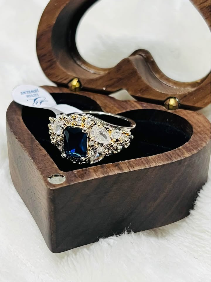 Side view of a beautiful shining sapphire and diamond ring displayed in a heart-shaped wooden box.