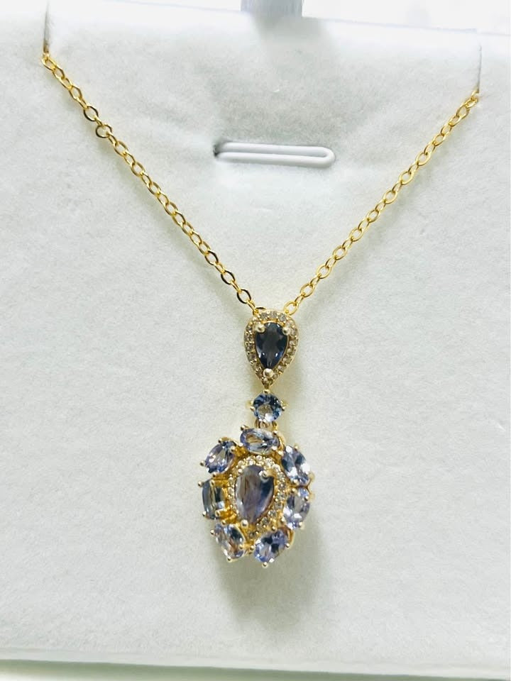 Elegant blue gemstone pendant featuring natural tanzanite and blue sapphires in white setting.
