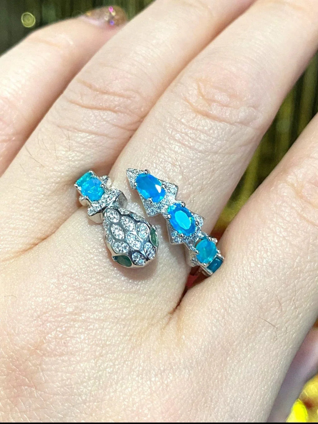 Stylish blue opal and zircon snake ring beautifully displayed on a finger, showcasing its fit and sparkle.