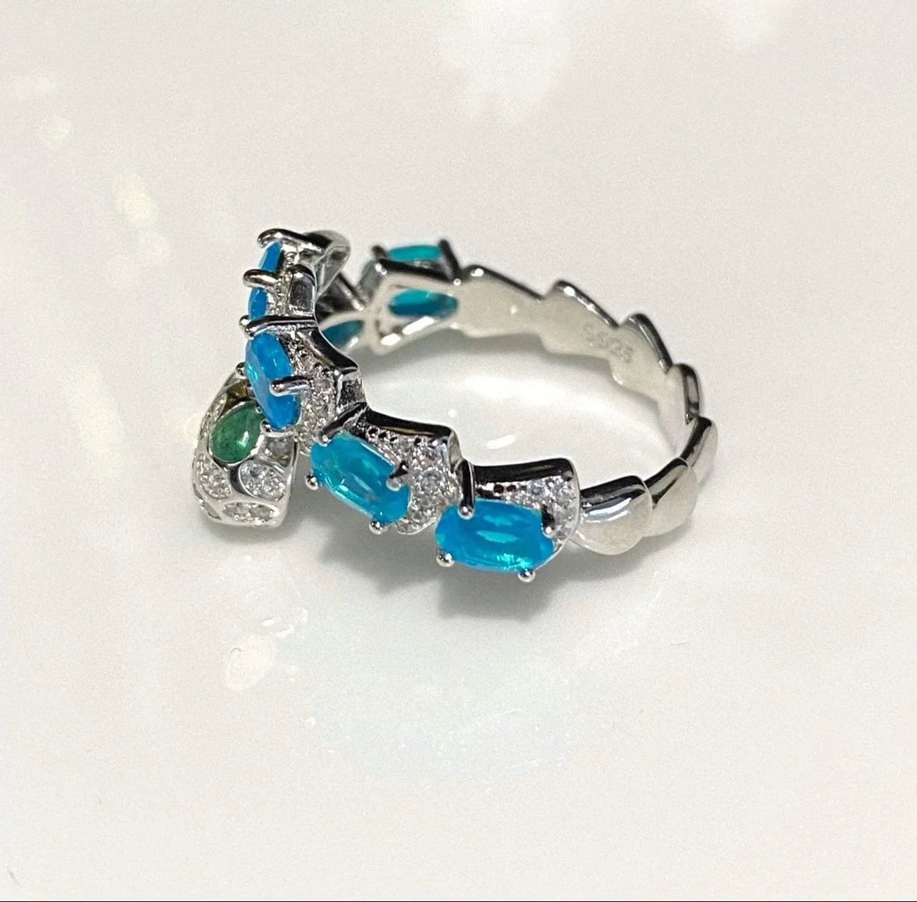 Side view of a stunning blue opal and zircon snake ring in sterling silver, highlighting the band's design.