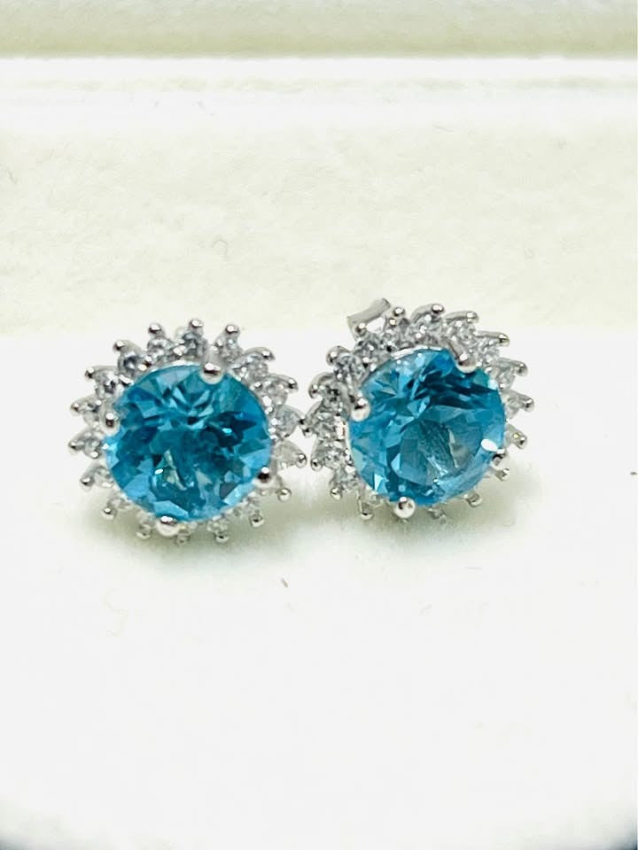 Stunning pair of blue topaz halo earrings, featuring vibrant blue stones in sterling silver.